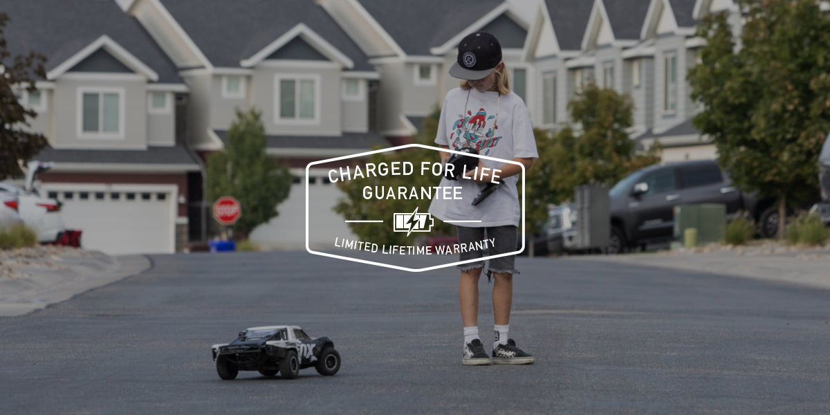 A young boy playing with an RC truck on a neighborhood street with the Paleblue Lifetime Warranty logo